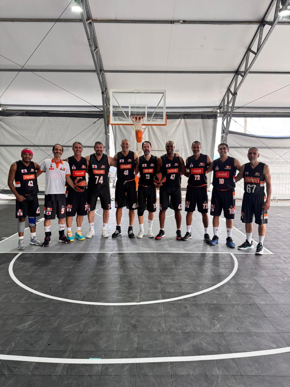 Time da ABM Inconfidentes com uniforme preto e laranja em quadra